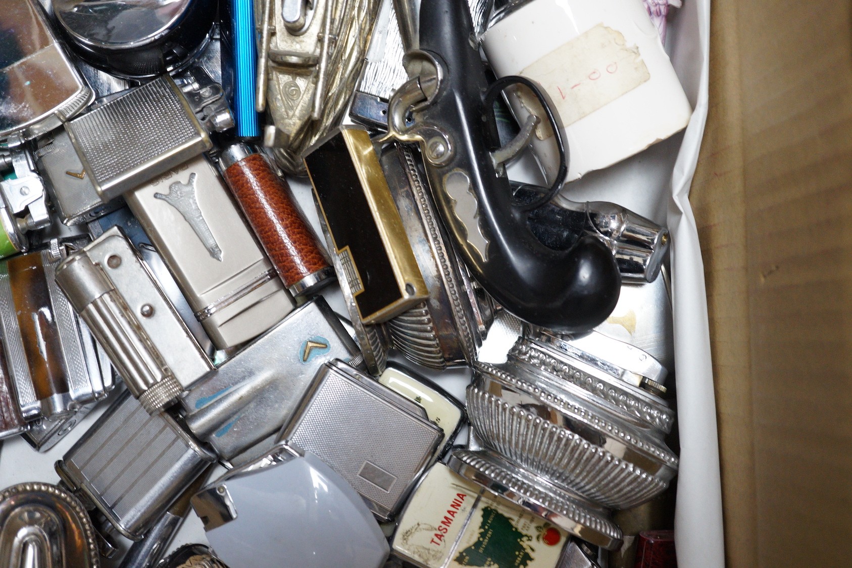 A collection of lighters including some novelty examples such as a percussion cup pistol, a KKW lighter camera, and a spy camera lighter